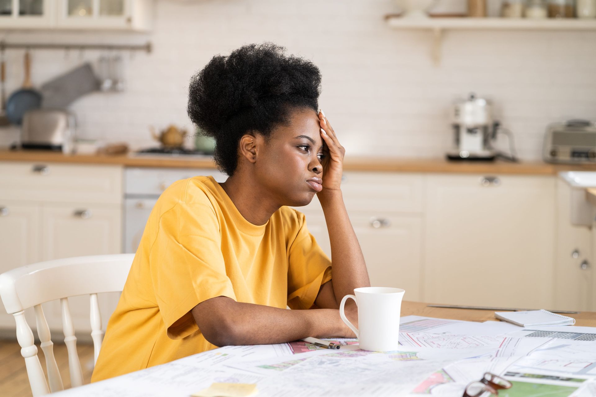  A woman at a kitchen table tired and overwhelmed, reflecting about dementia caregiver burnout