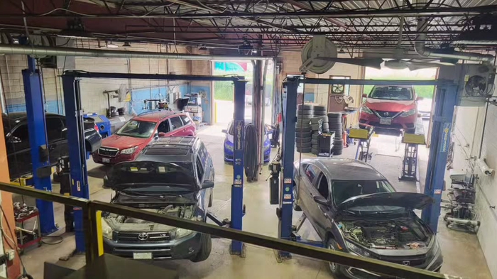 Auto repair shop with several cars on lifts and in service bays inside a busy garage | SAI Automotive Inc.