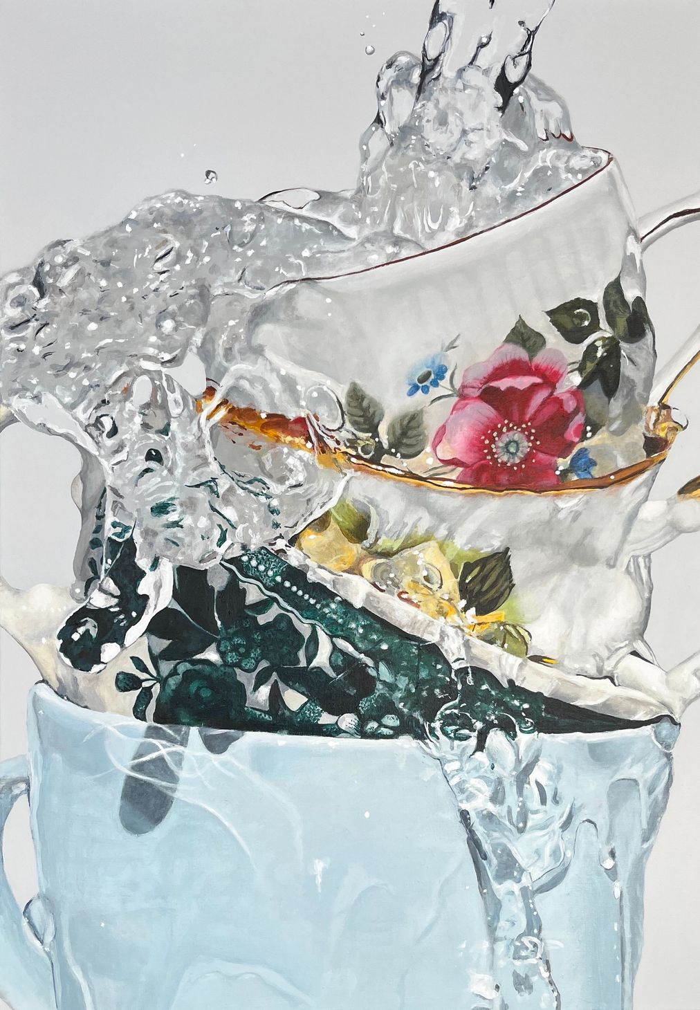 Gestapelde theekopjes met bloemenmotief die in een glas water spatten, tegen een lichte achtergrond.