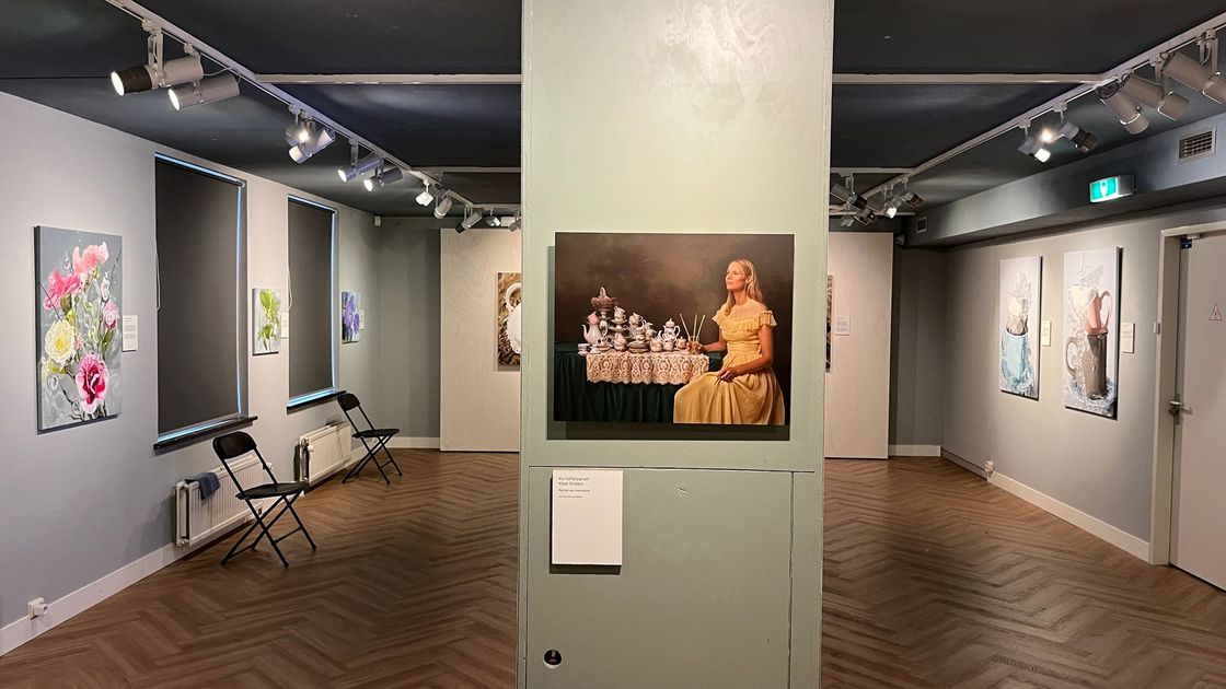 Interieur van het Huizer Museum met ingelijste schilderijen aan witte muren en een centrale pilaar waarop een groot kunstwerk staat.