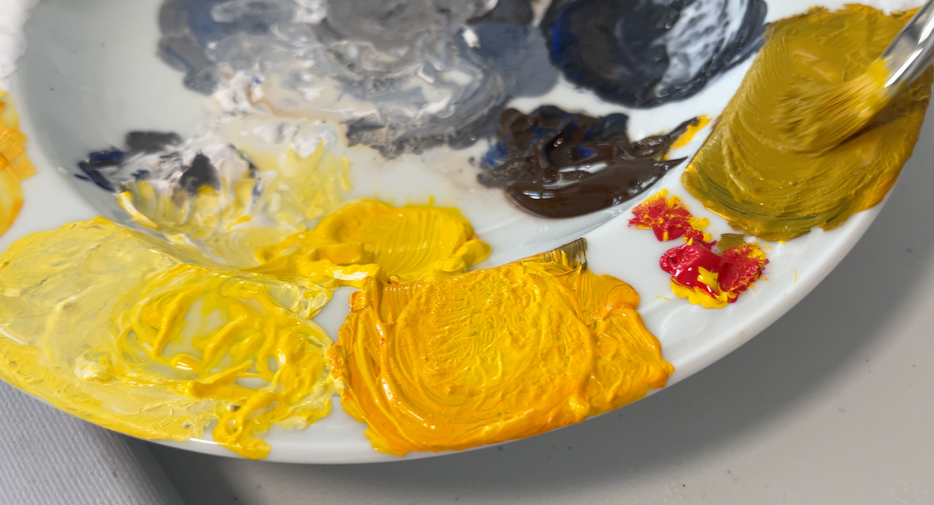 Verfpalet met gele, oranje, grijze, zwarte en rode verfvlekken op een witte ondergrond