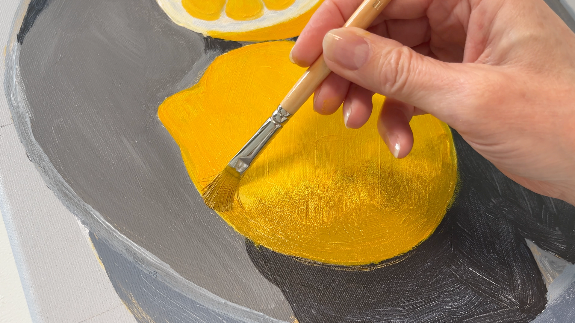 Een kwast met gele acrylverf  op een grijze schaal voor een online schildercursus.