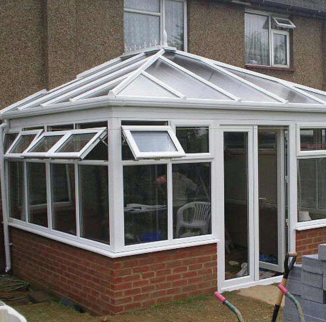 A conservatory is being built on the side of a brick house.