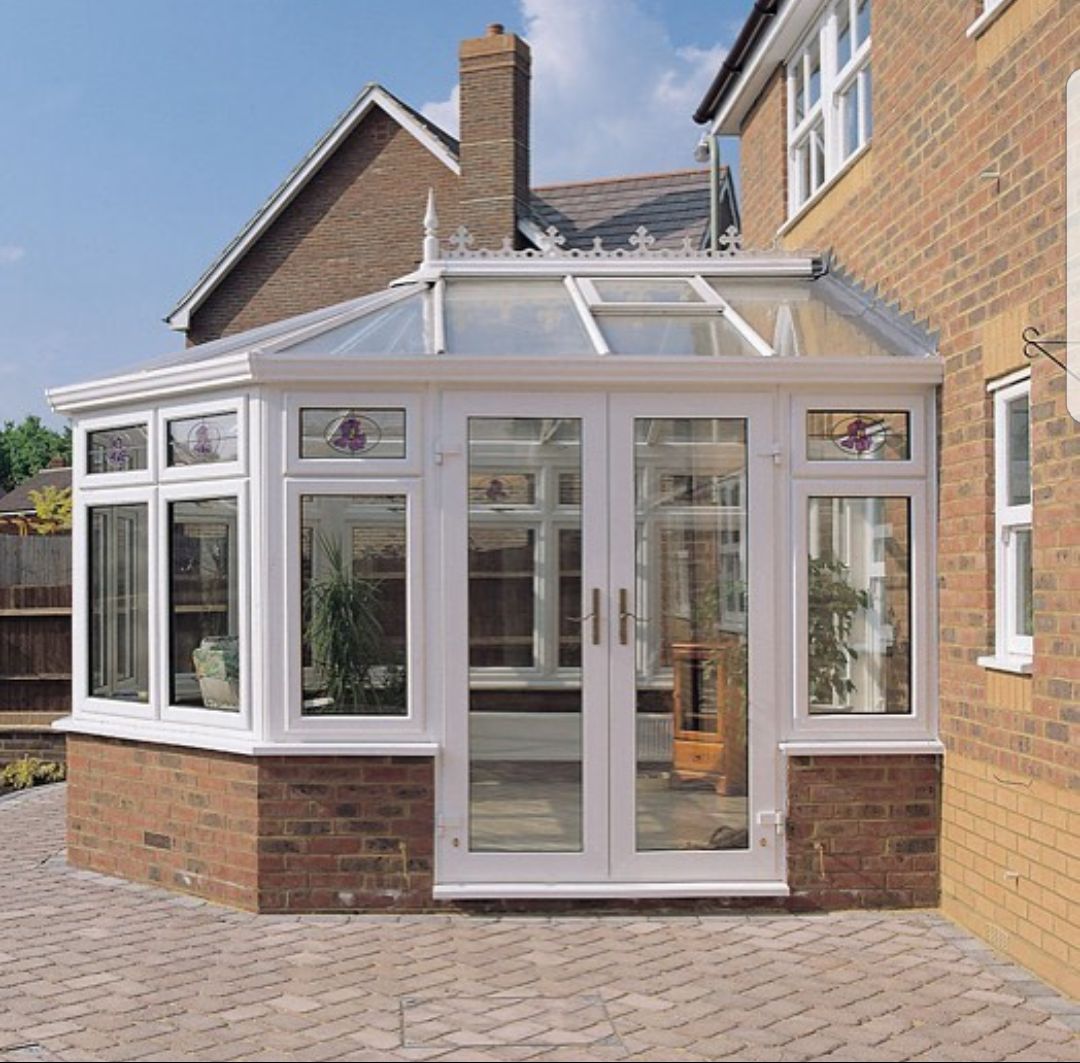 A brick house with a glass conservatory on the side