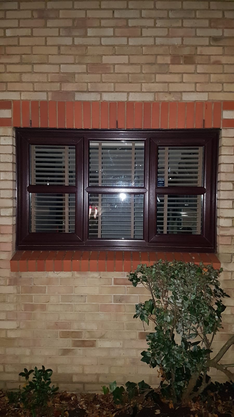 A window on the side of a brick building with blinds.