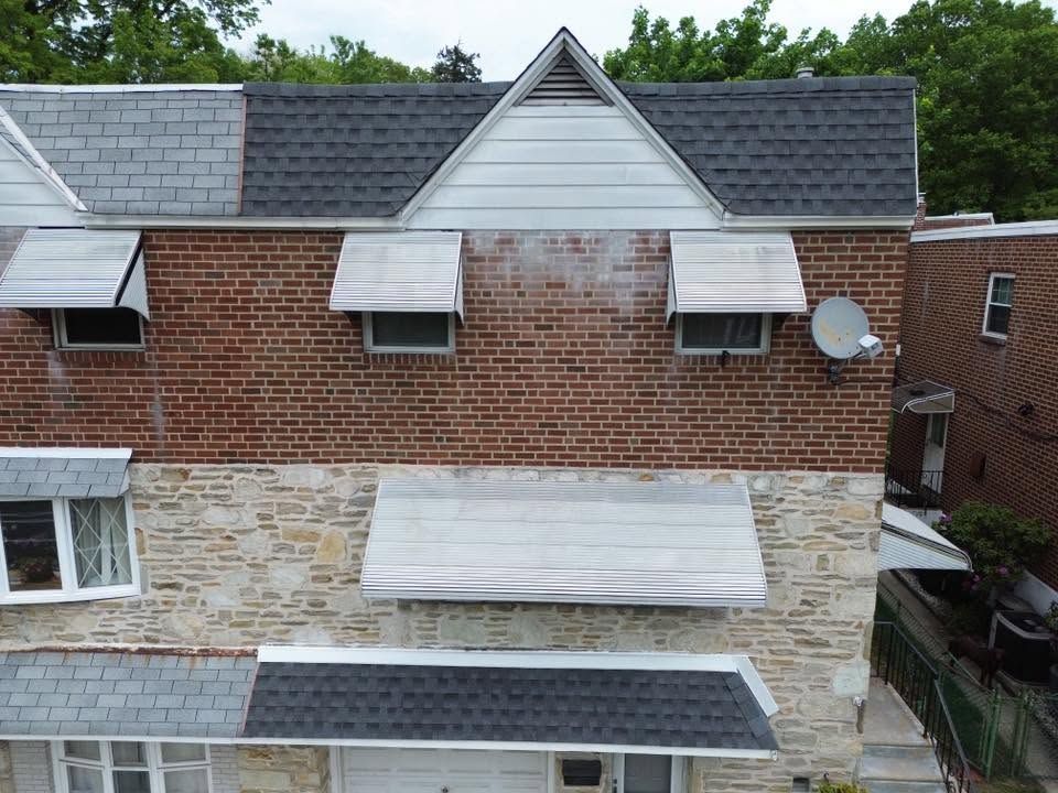 Brick and stone townhouse exterior with gray shingle roof and dormer windows