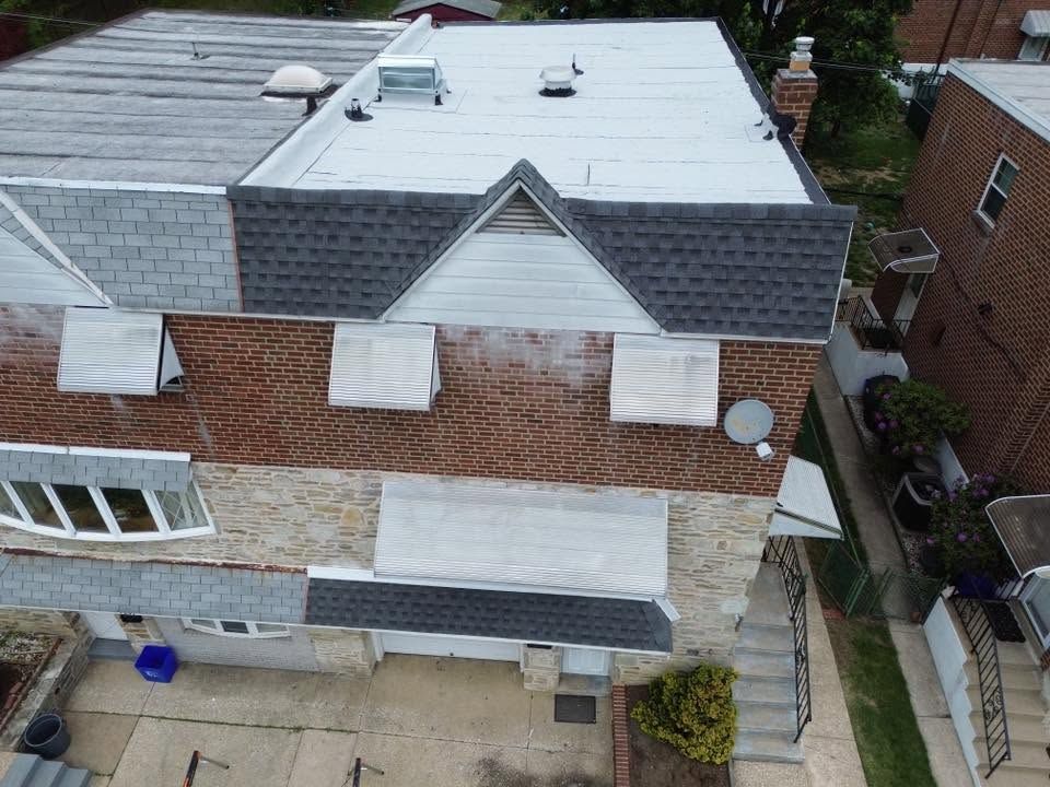 Aerial view of a two-story house with a white flat roof, brick siding, and a small backyard.