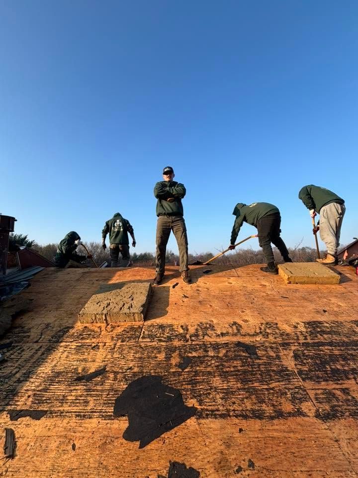 Workers standing and bending on a sunlit roof under a clear blue sky
