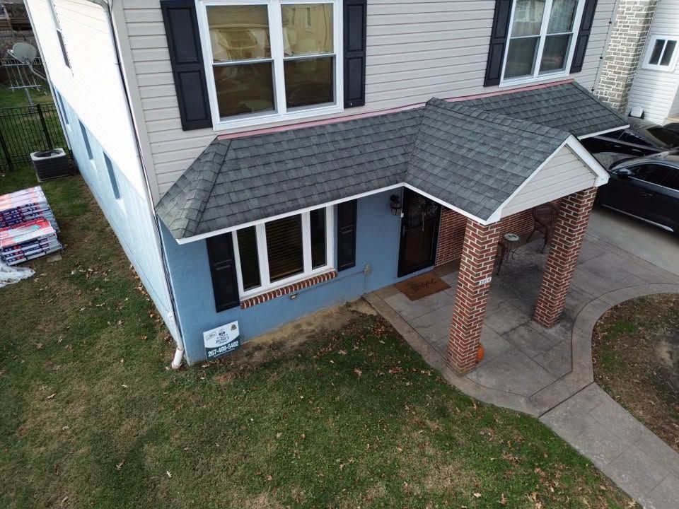 Front entrance of a house with a gray roof, brick columns, and a small lawn.