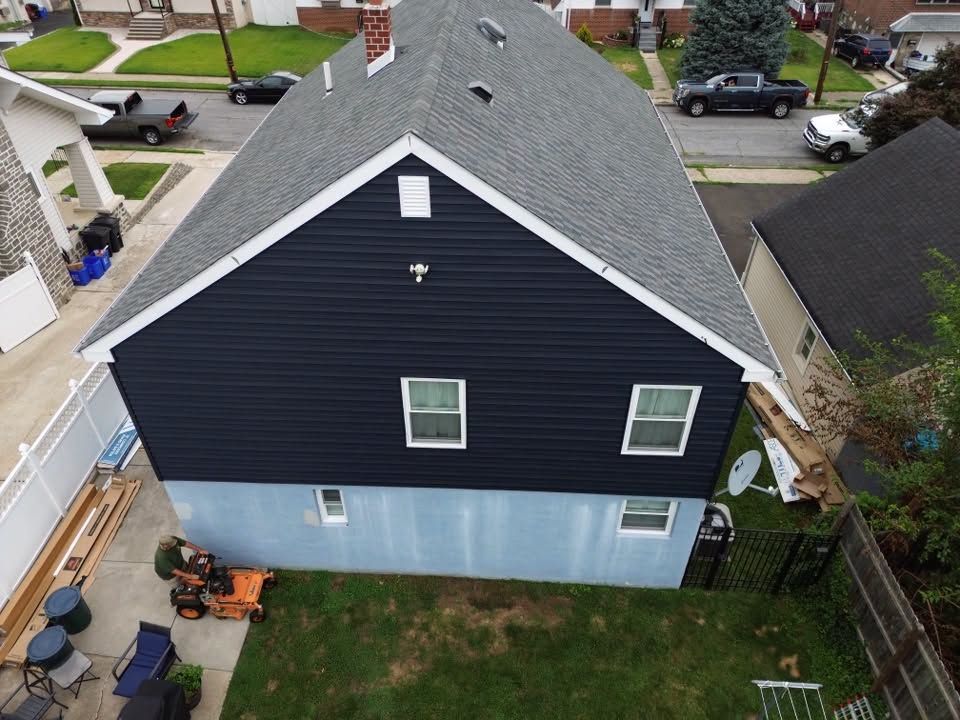 Aerial view of a dark blue house with a light blue foundation and small backyard patio.