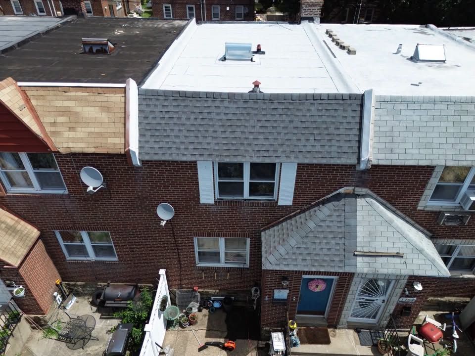 Aerial view of rowhouses with brick facades, white roofs, and small front stoops.