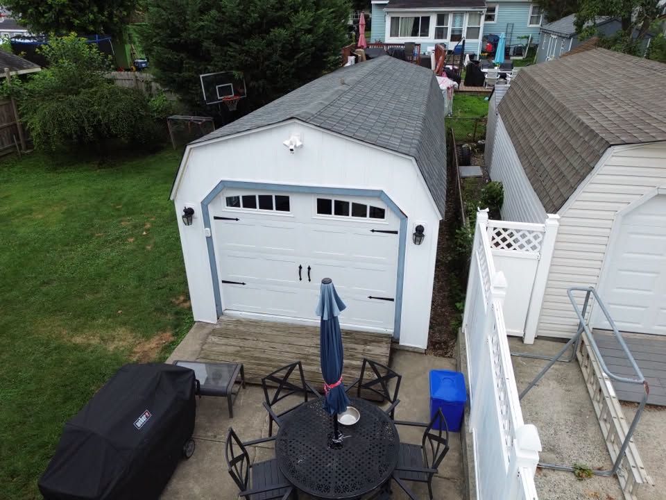 Backyard patio with a white garage, black grill cover, patio table, and umbrella on a fenced deck