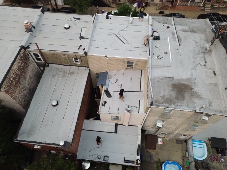 Aerial view of flat rooftops in an urban neighborhood, with a few people standing on one roof.