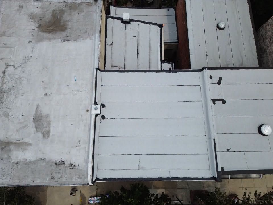 Aerial view of weathered white wooden rooftops with a narrow gap and a small vent.