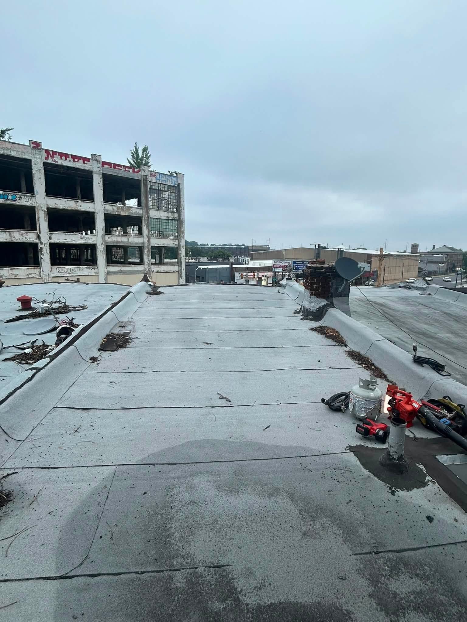 Rooftop with scattered debris and a damaged building under a gray sky