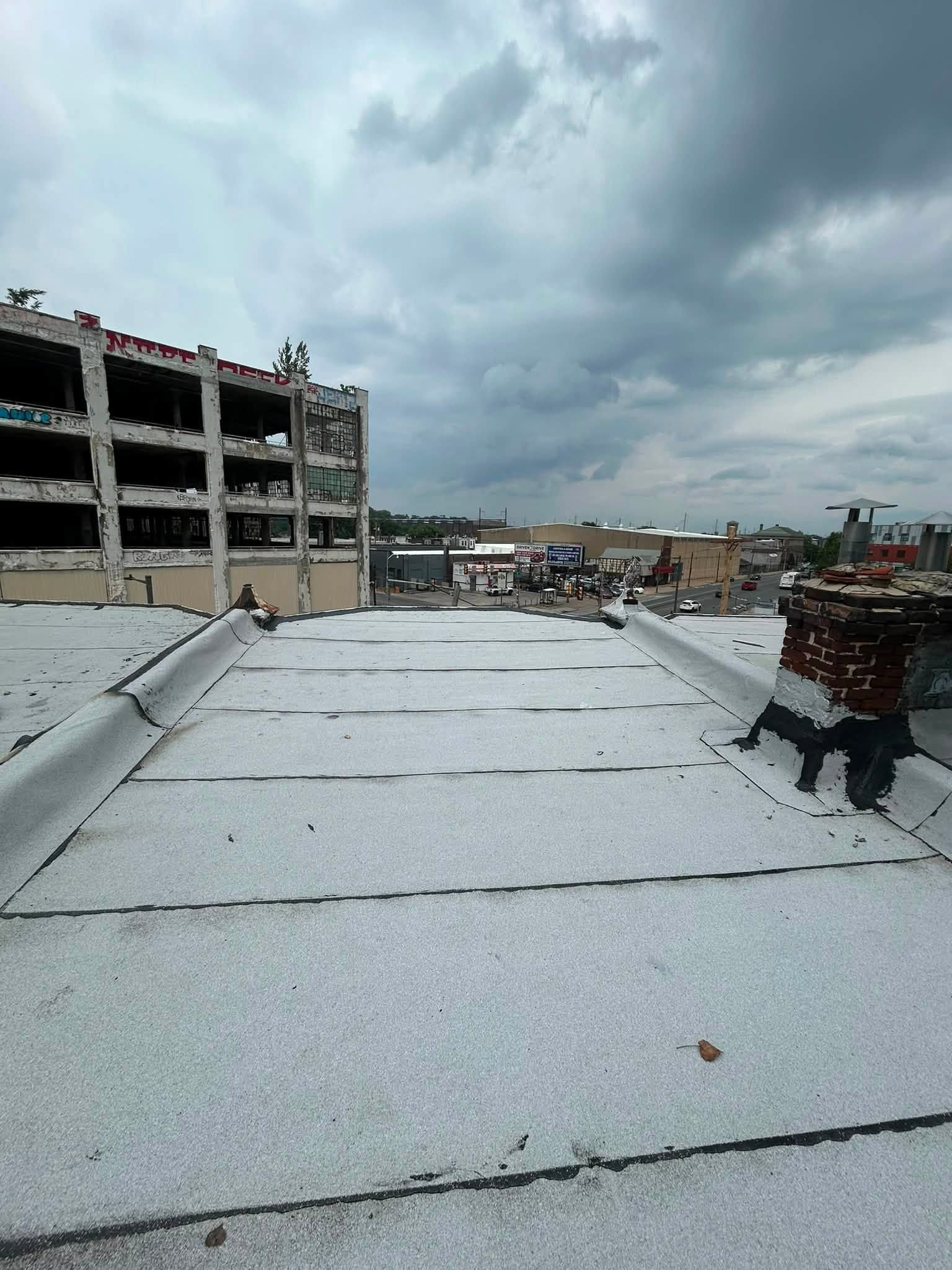 Rooftop under cloudy sky beside a damaged building and city skyline