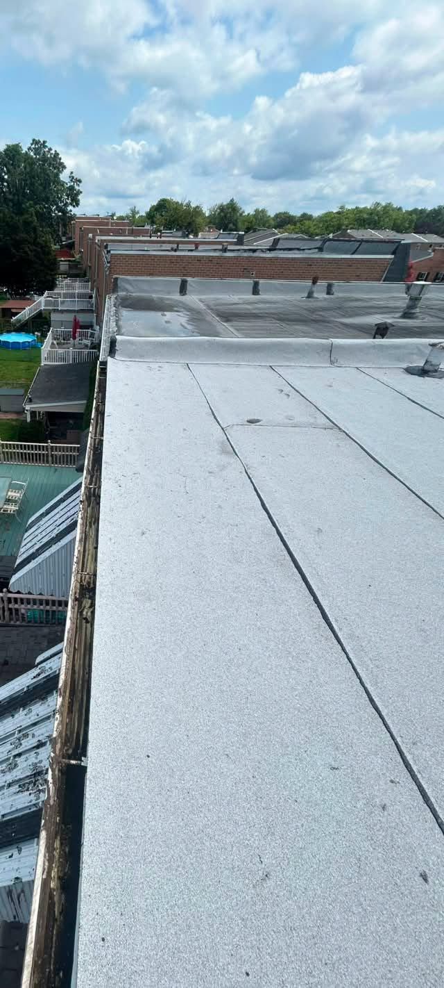 Rooftop with silver metal panels under a cloudy sky, overlooking trees and nearby buildings