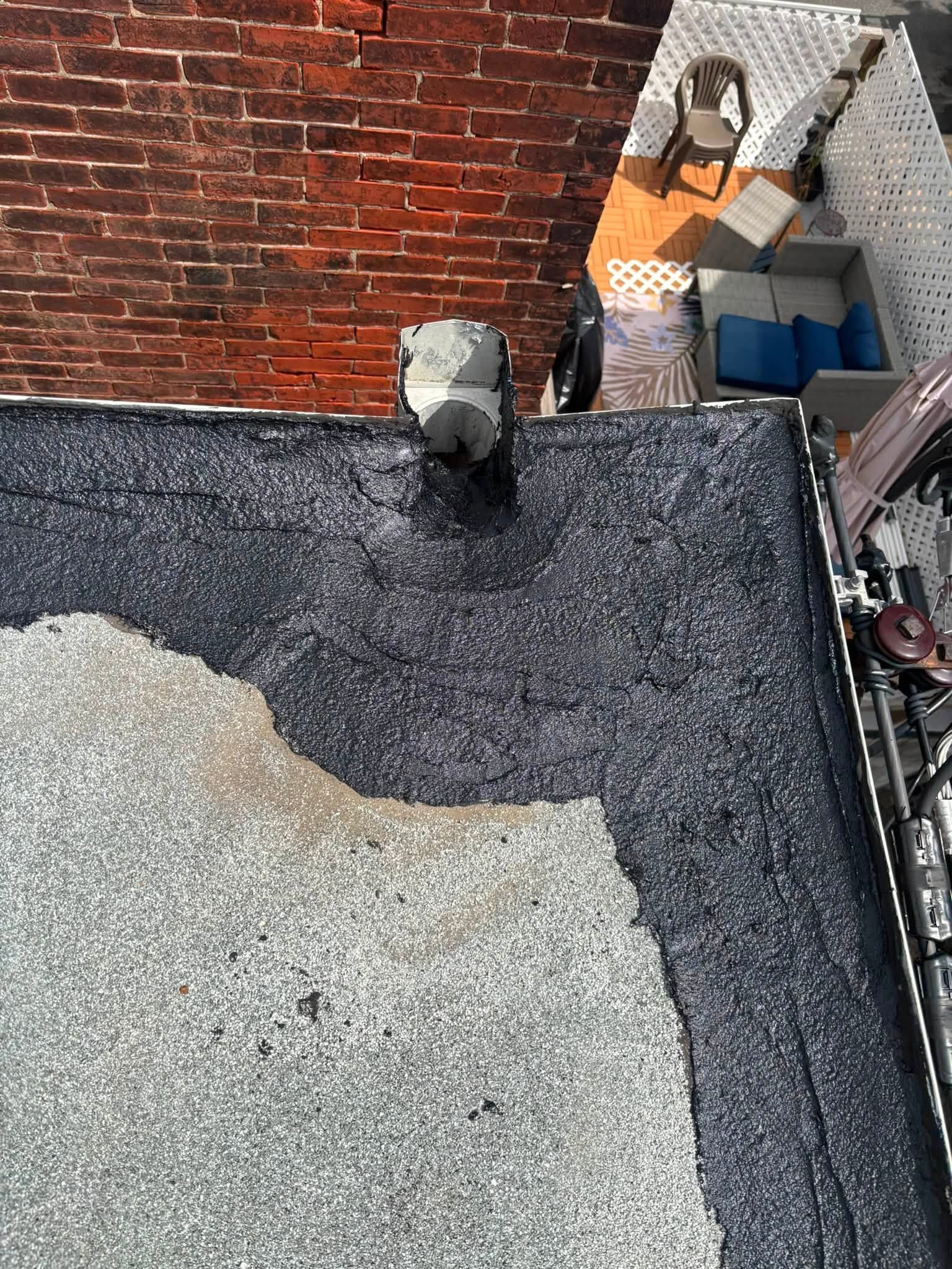 Rooftop with black gravel, red brick wall, and a small utility area with boxes and equipment