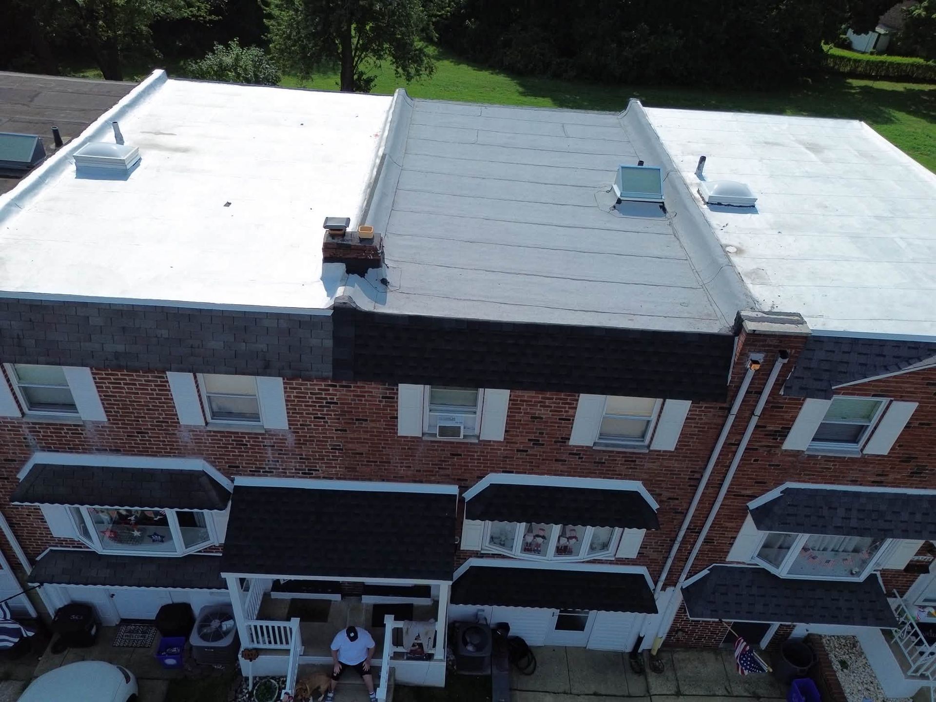Aerial view of brick row houses with white flat roofs and small back patios.