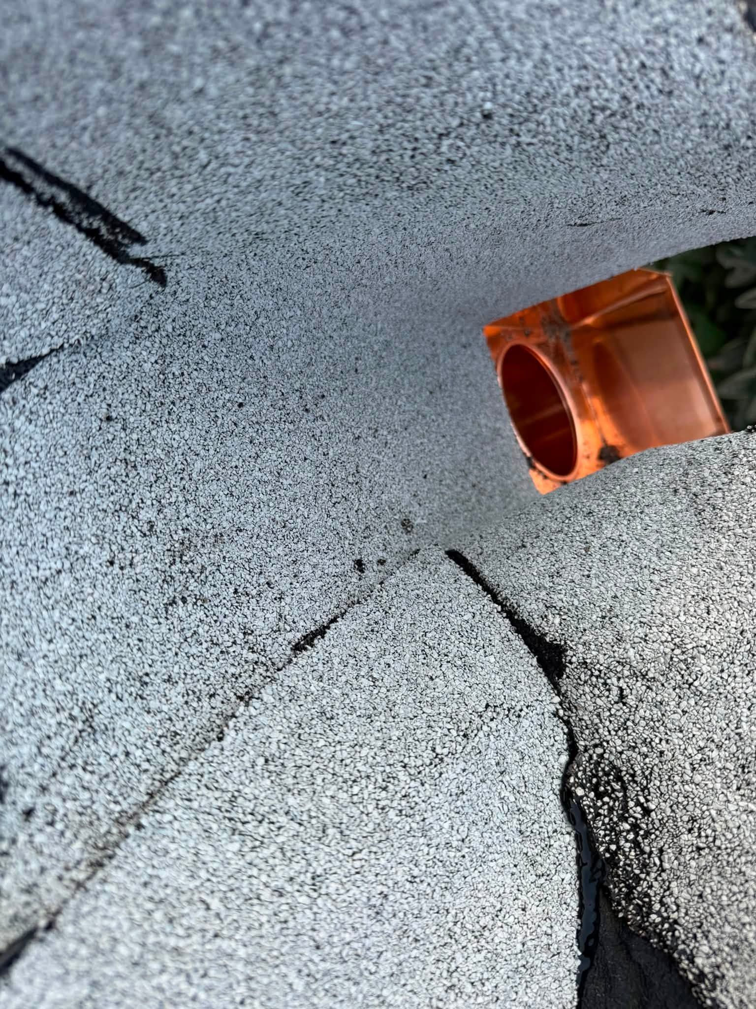 Orange pipe protruding from a gray textured ceiling with a crack nearby