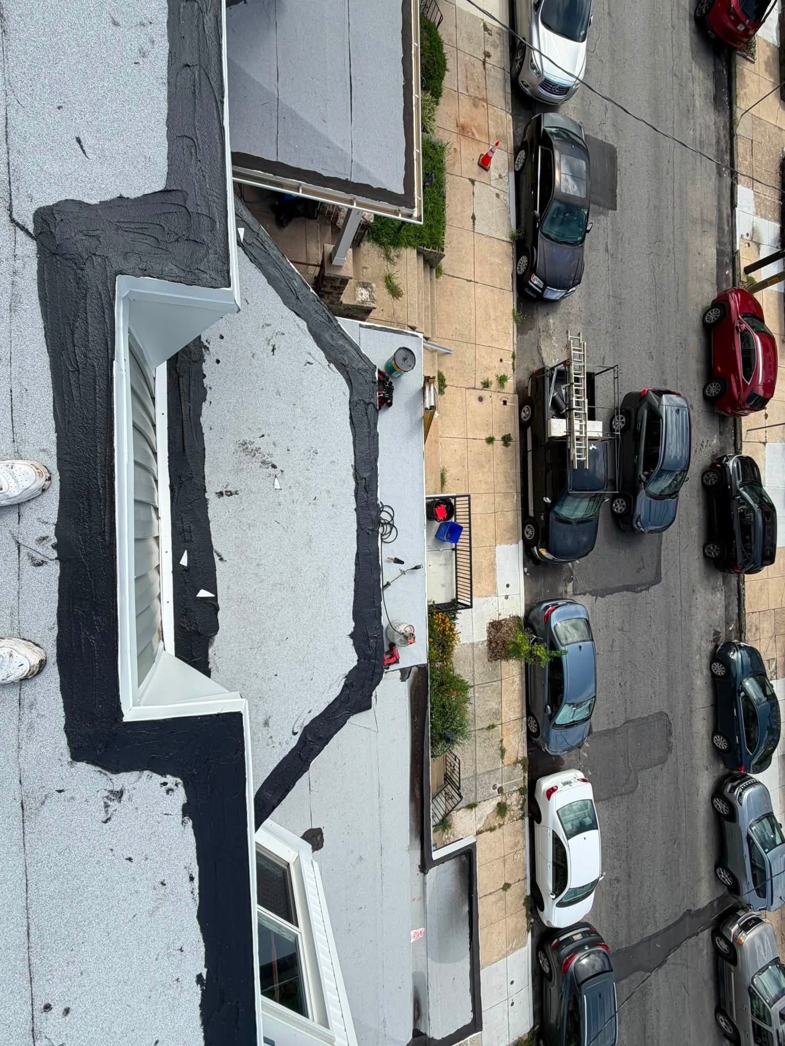 Overhead view of parked cars beside a gray rooftop and sidewalk in an urban street scene