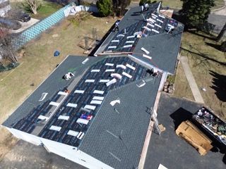 Aerial view of a roof covered with scattered white debris and several people working on it