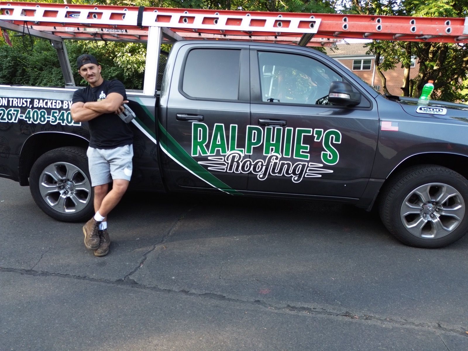 Man leaning on a black truck with a red ladder on top, branded “Ralphie’s Painting.”