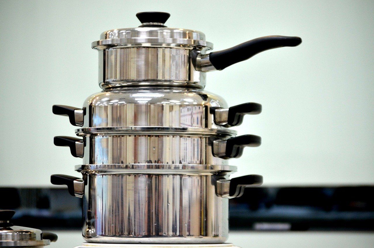 Stacked stainless steel steamer pots with black handles and lid knob.