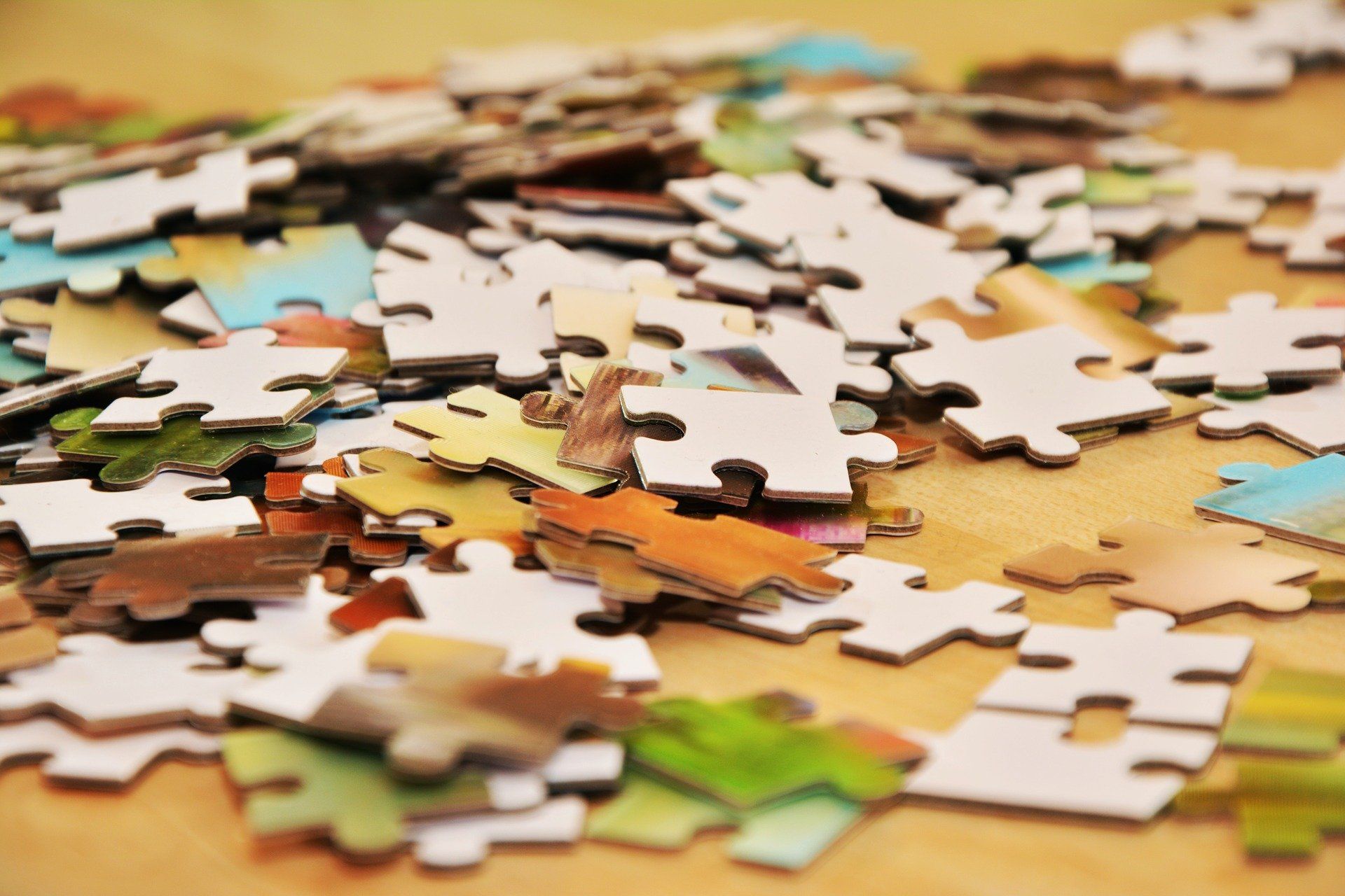 Scattered jigsaw puzzle pieces in various colors on a wooden surface.