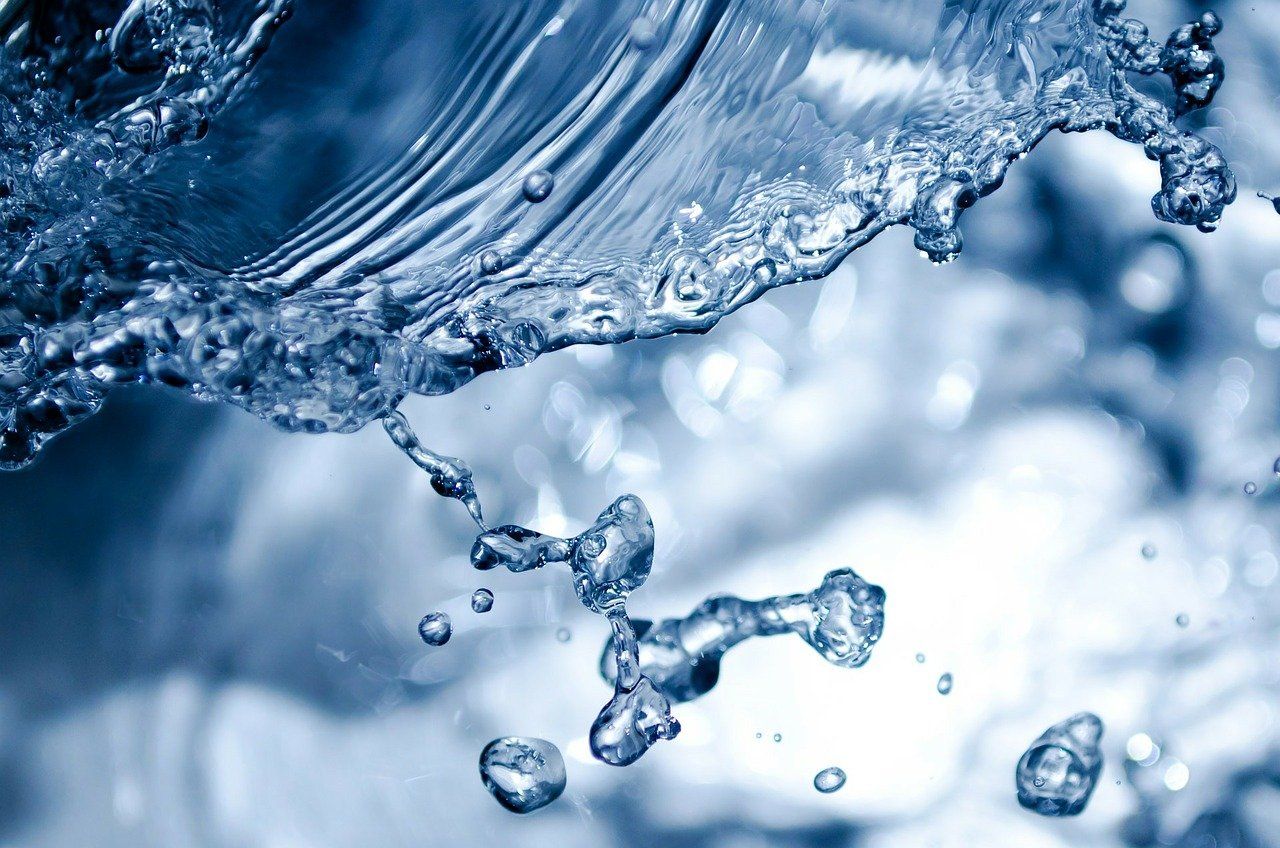 Close-up of clear water splashing, with droplets and flowing patterns in shades of blue.