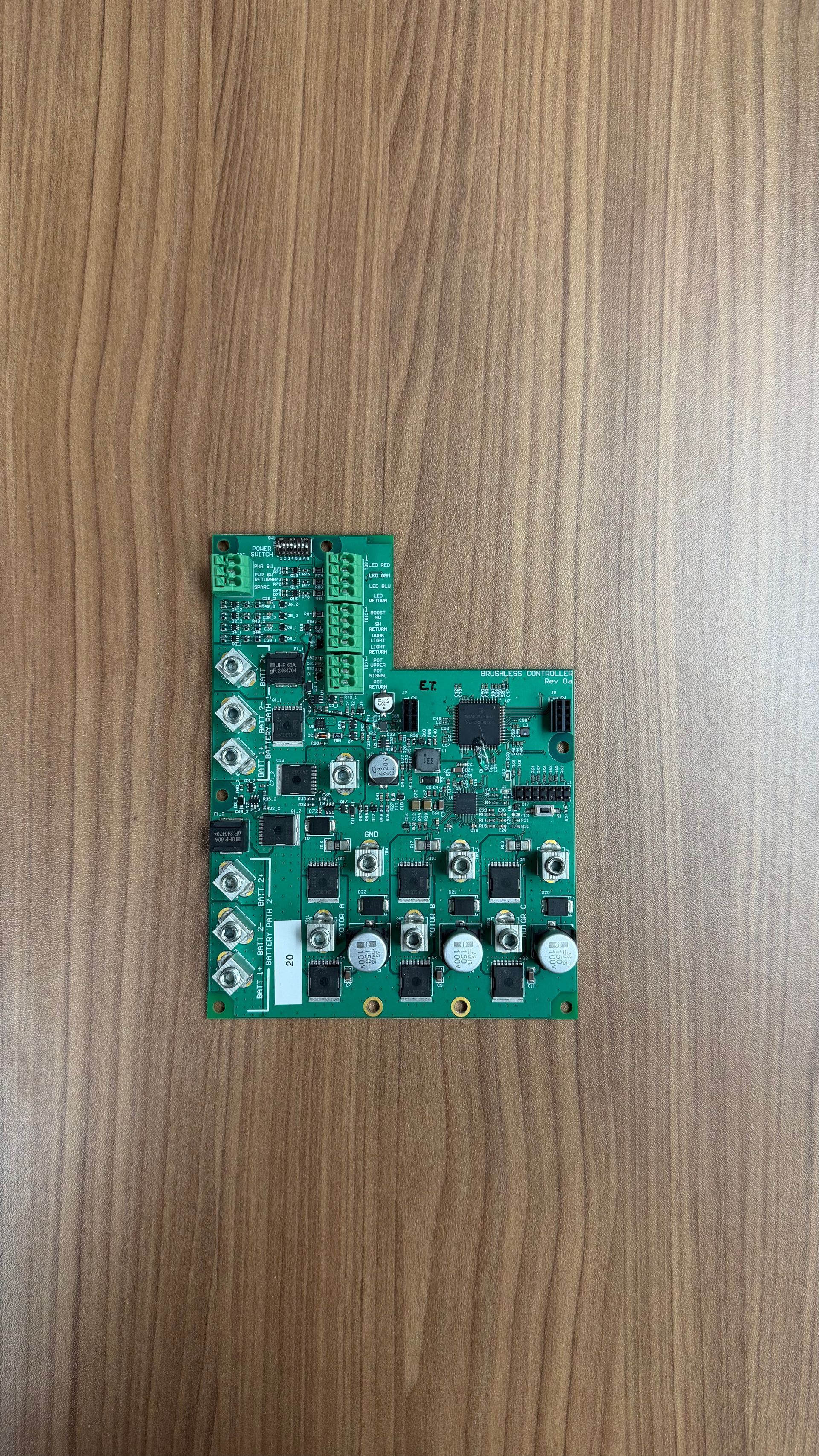 A green rectangular circuit board with various electronic components, connectors, and silver circular terminals.