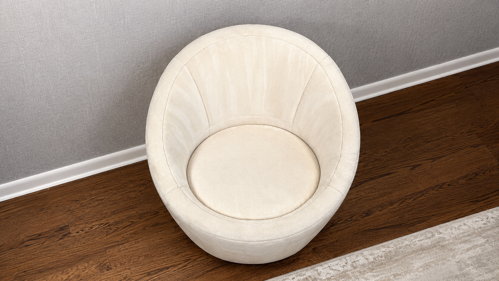 Cream upholstered accent chair against a gray wall on a dark wood floor.