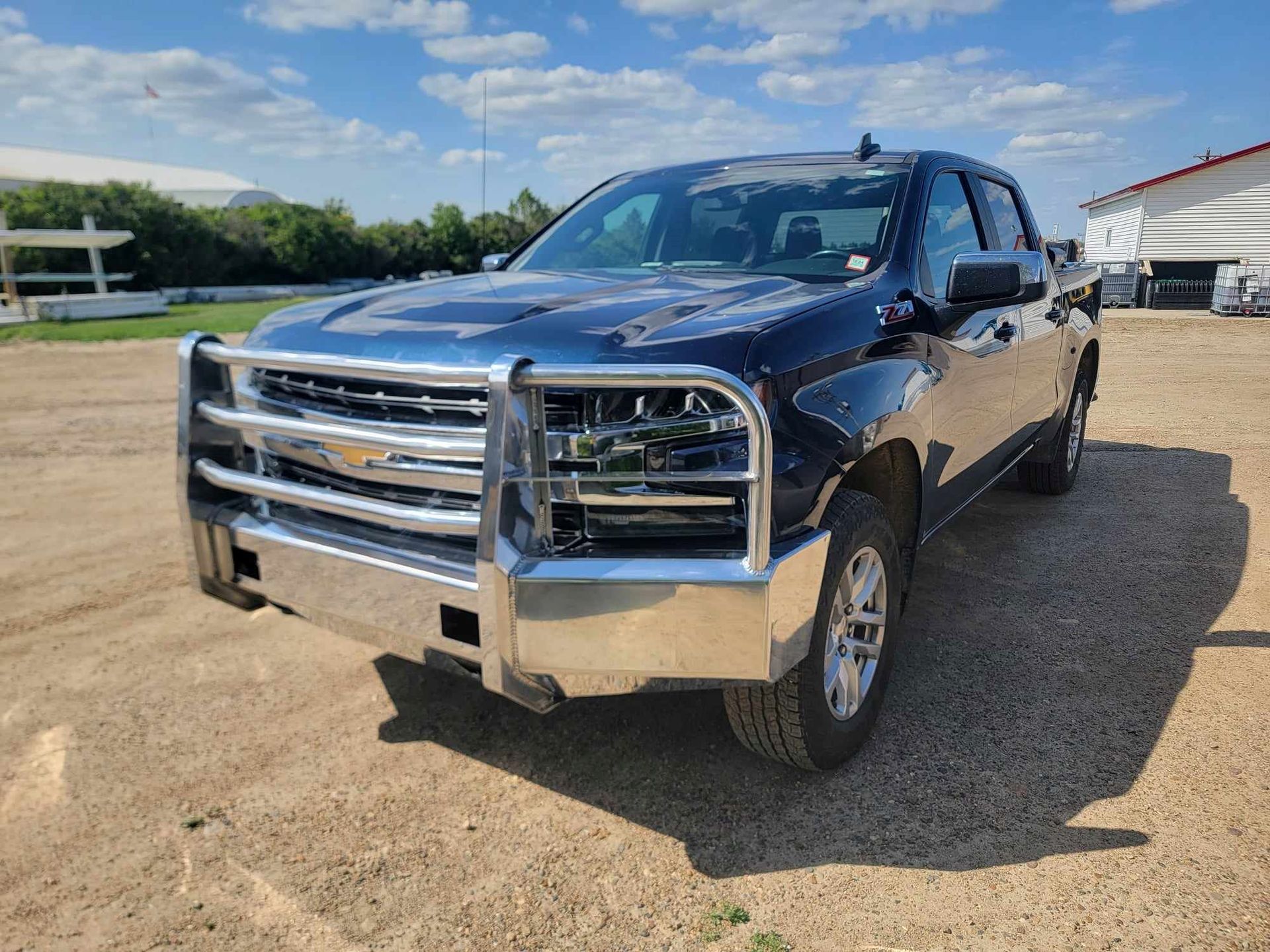 A black truck with a chrome bumper is parked in a gravel lot.