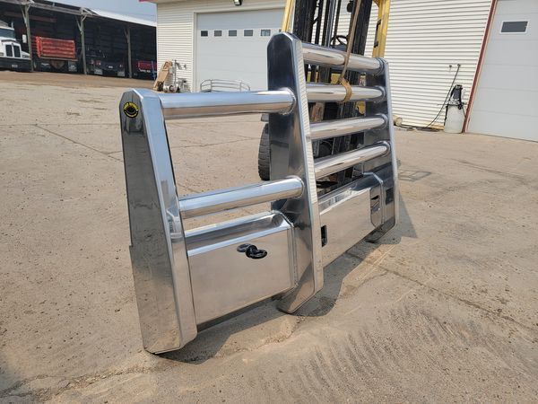 A stainless steel bumper is sitting on the ground in front of a forklift