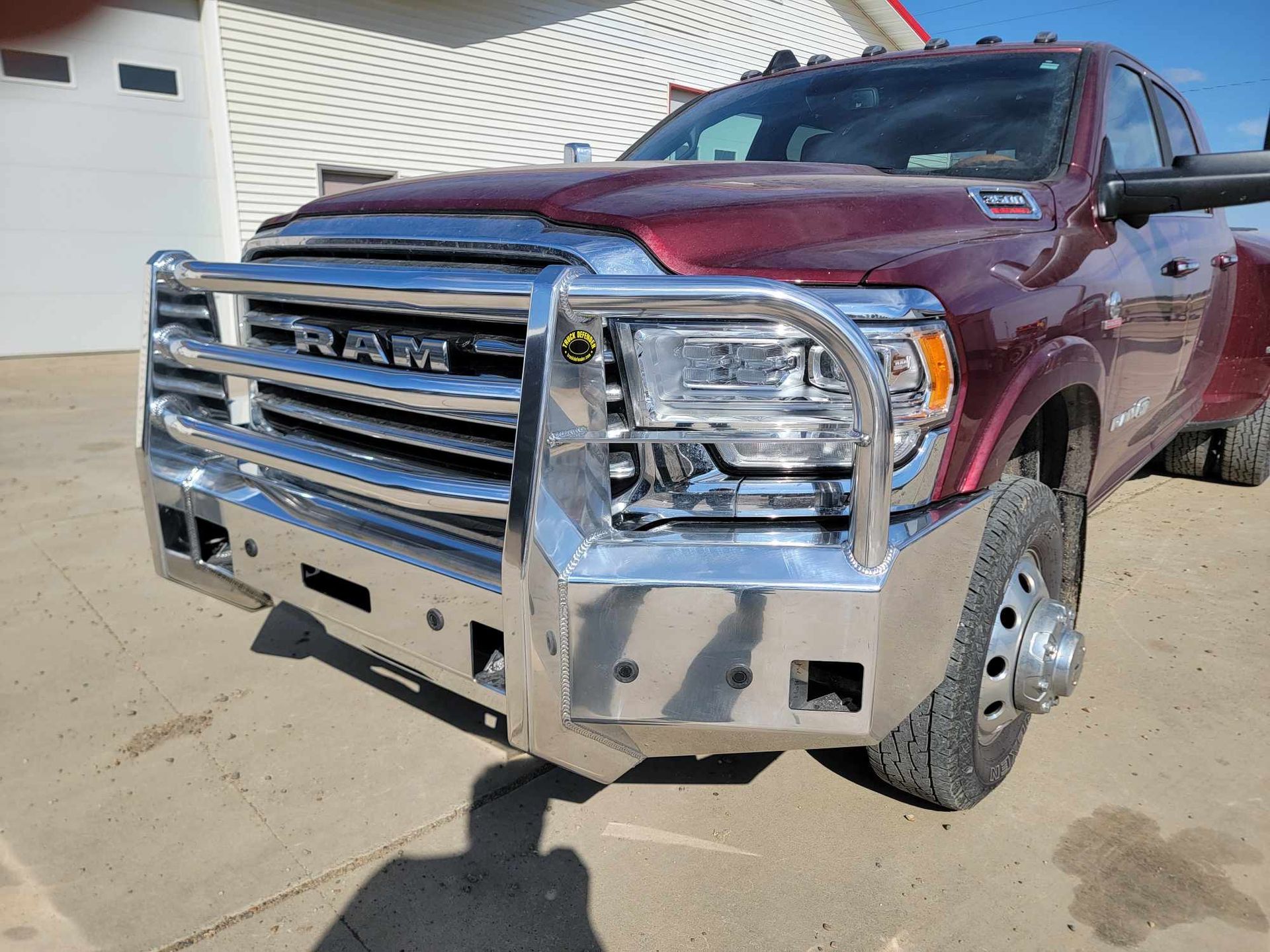 A red ram truck with a chrome bumper is parked in front of a garage.