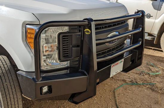 A silver truck with a black bumper is parked on the side of the road.