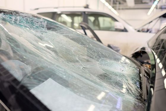 A car with a broken windshield is sitting in a garage.