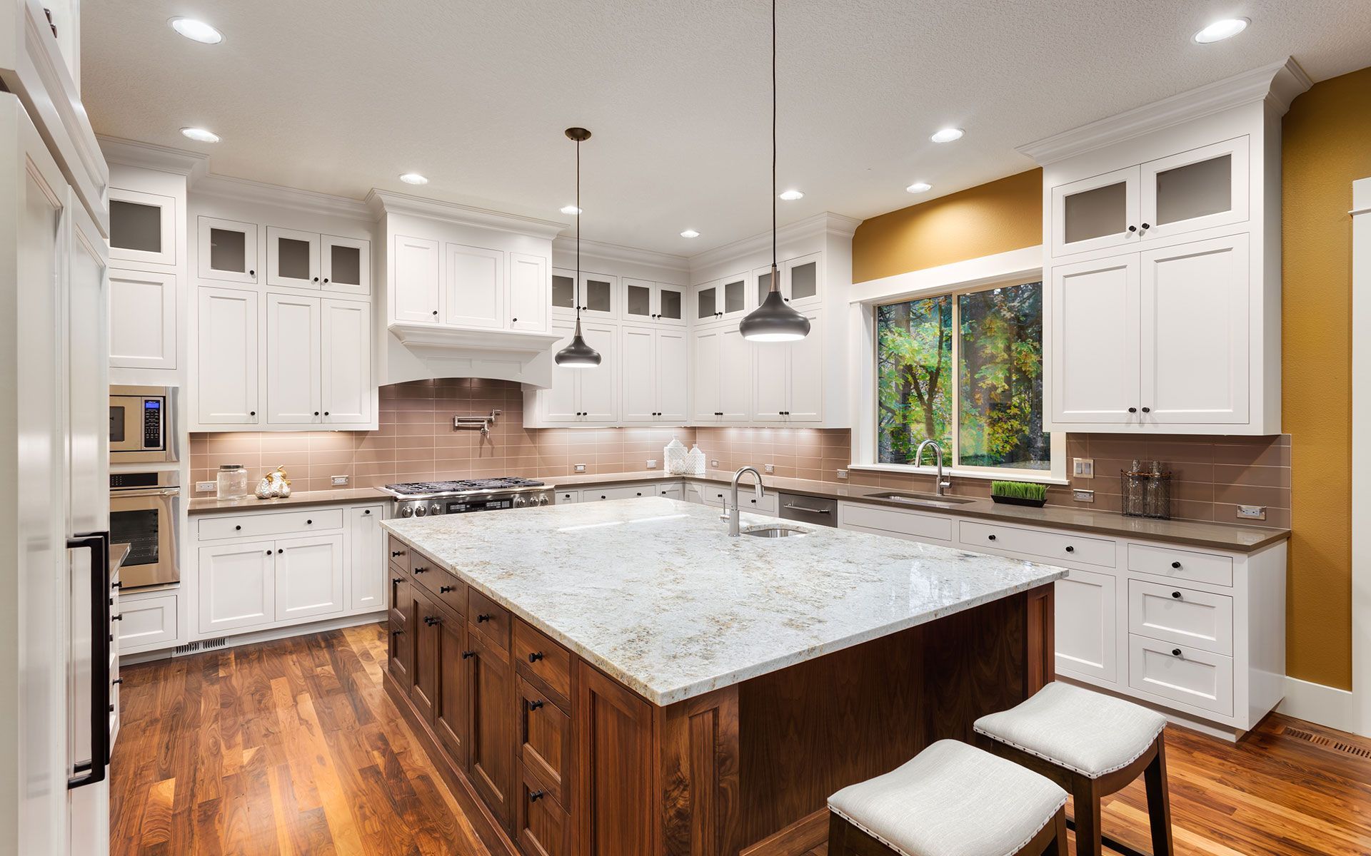 Bright kitchen with white cabinets, wood island, granite countertop, and wooden floor.