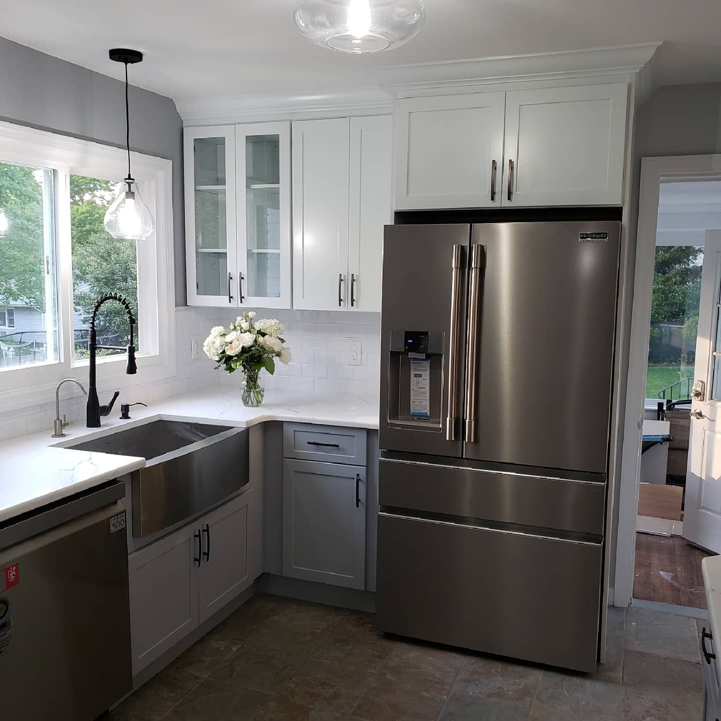 Modern kitchen with white and gray cabinets, stainless steel appliances, and a farmhouse sink.