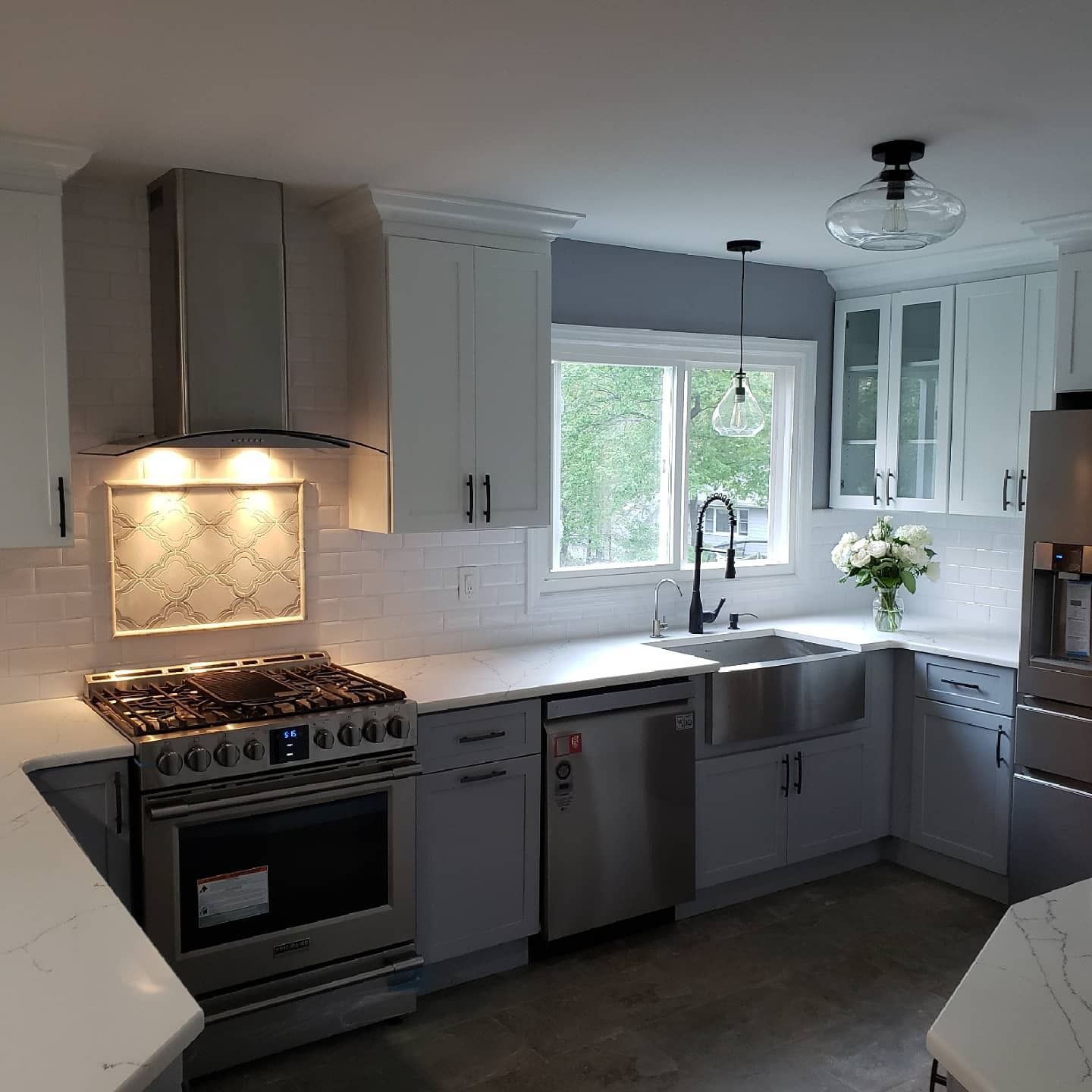 Modern kitchen with white and gray cabinets, stainless steel appliances, and a farmhouse sink.