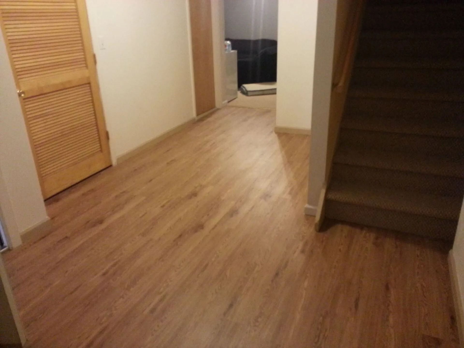 Wooden-floored hallway with a wooden door on the left and a staircase on the right.