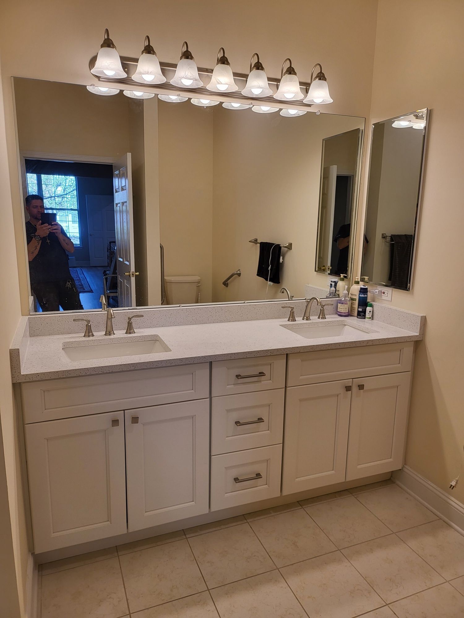 Bathroom with a white vanity, sinks, mirrors, and overhead lighting.