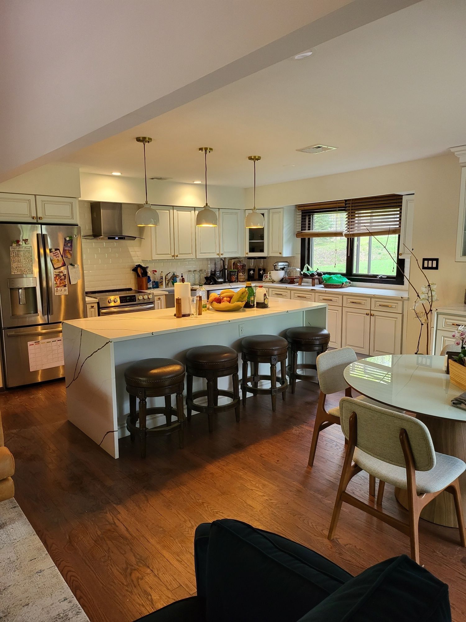 Kitchen with island seating, white cabinets, stainless steel appliances, and a dining table.