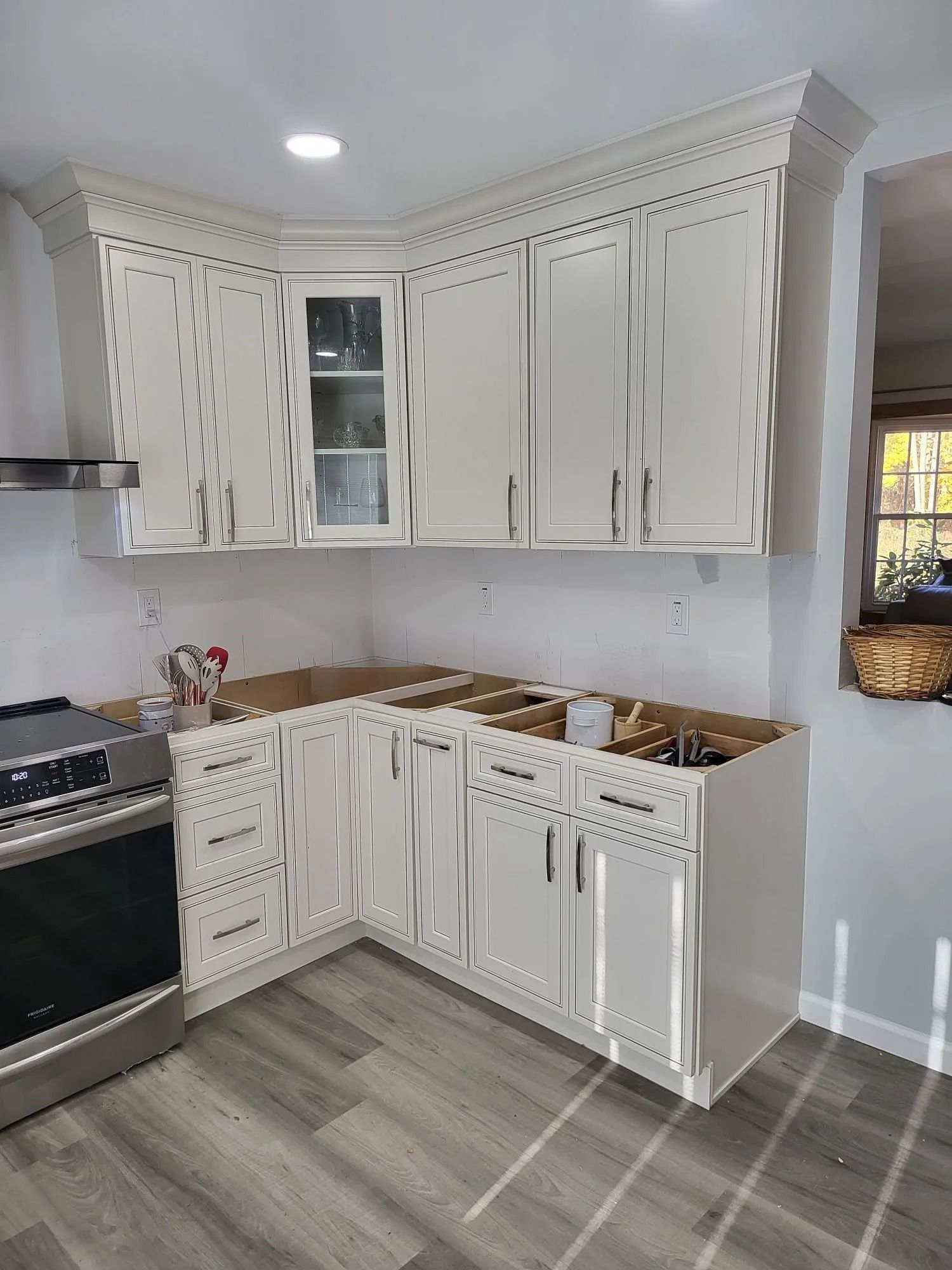 White kitchen cabinets being installed in a corner. Unfinished countertops.