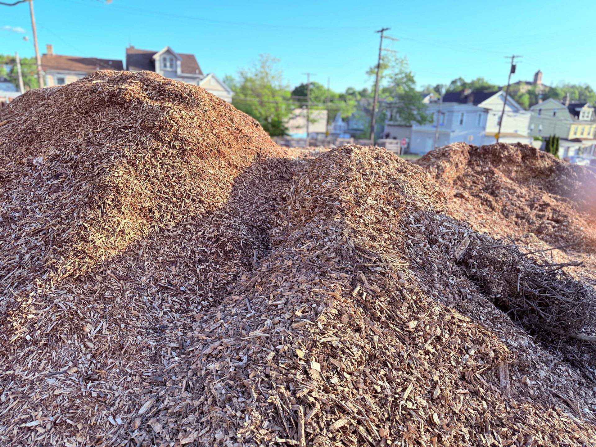 A pile of wood chips is sitting in front of a house.