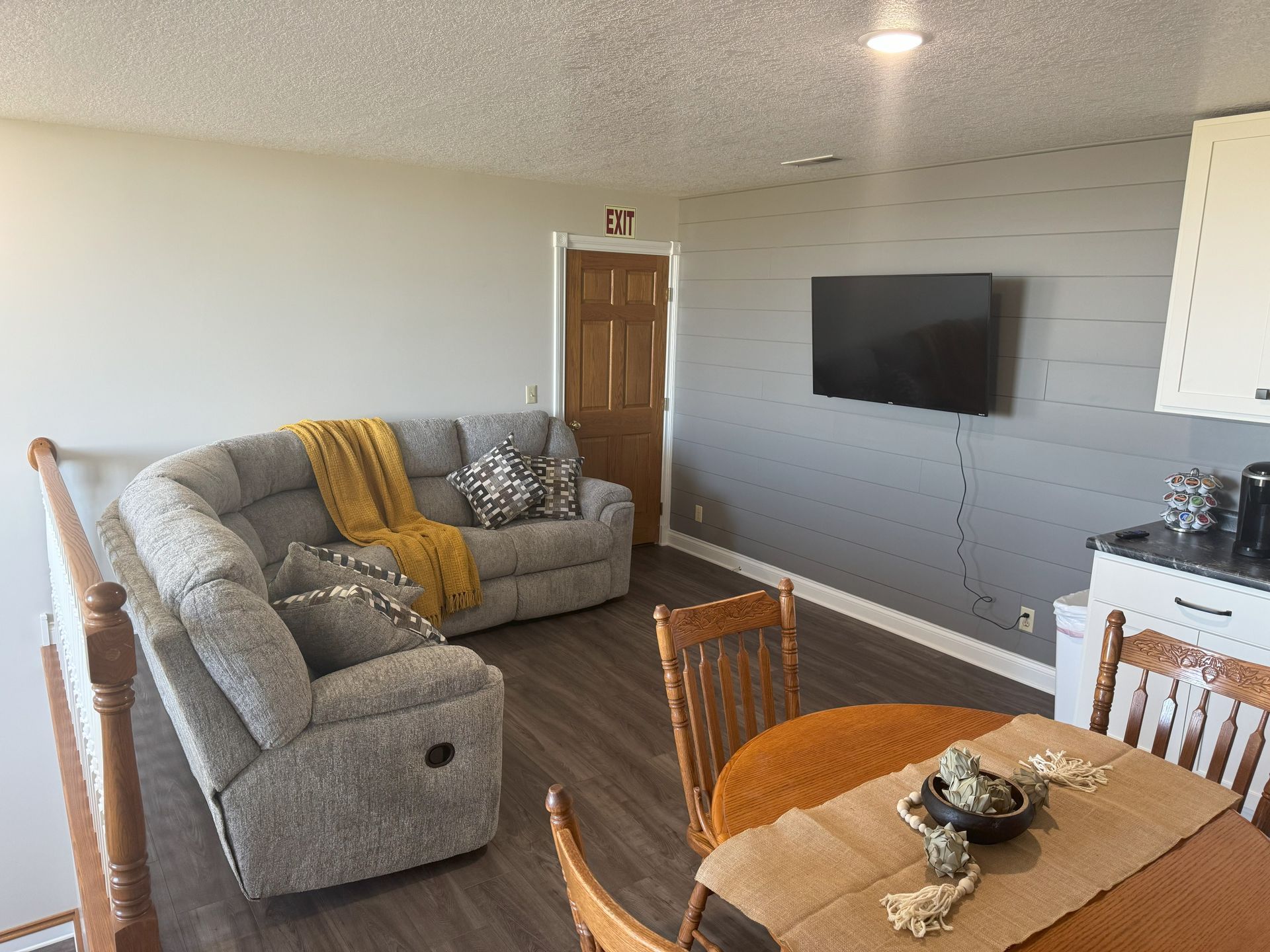 A living room with a couch , table , chairs and a flat screen tv.