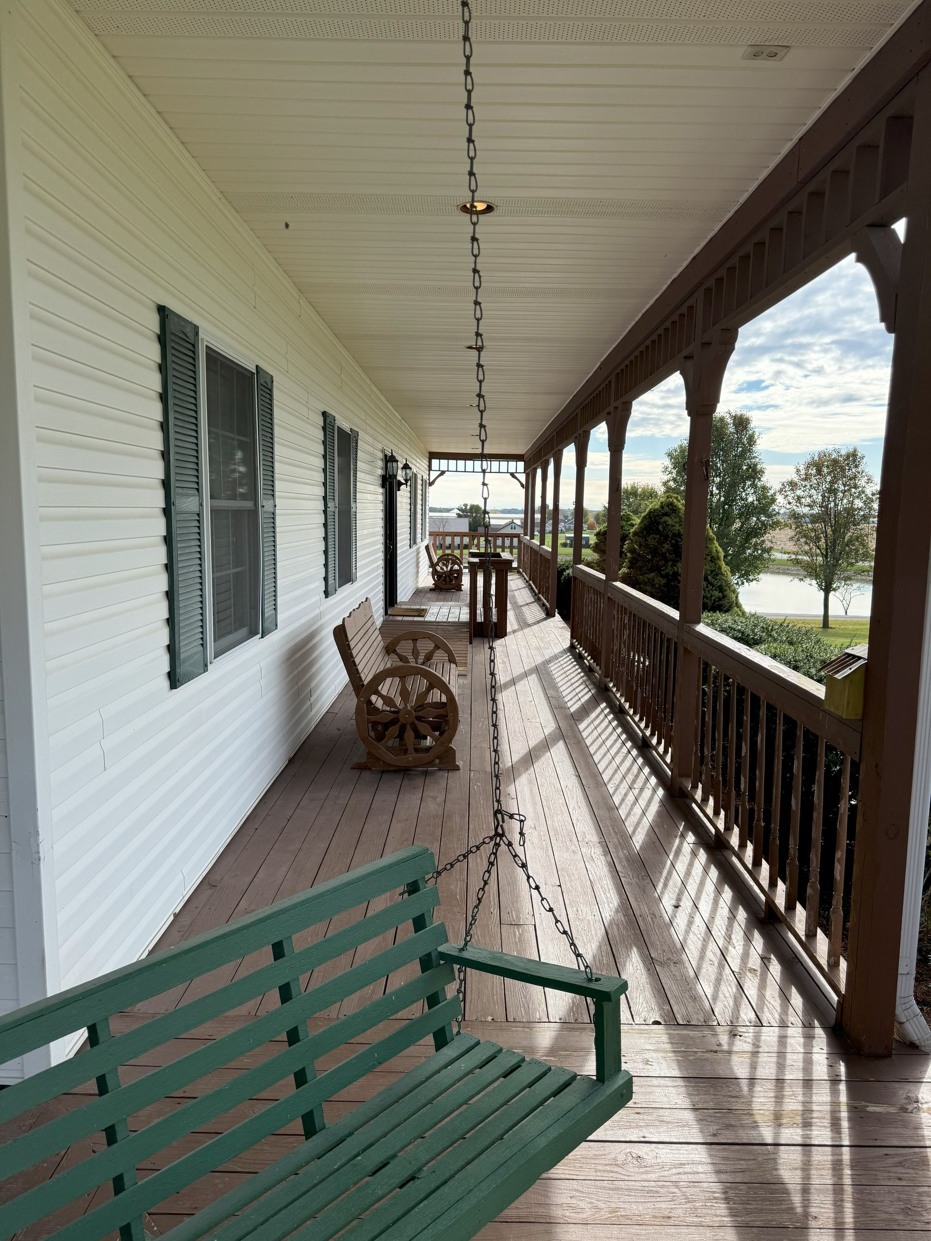 A porch with a green swing and rocking chairs