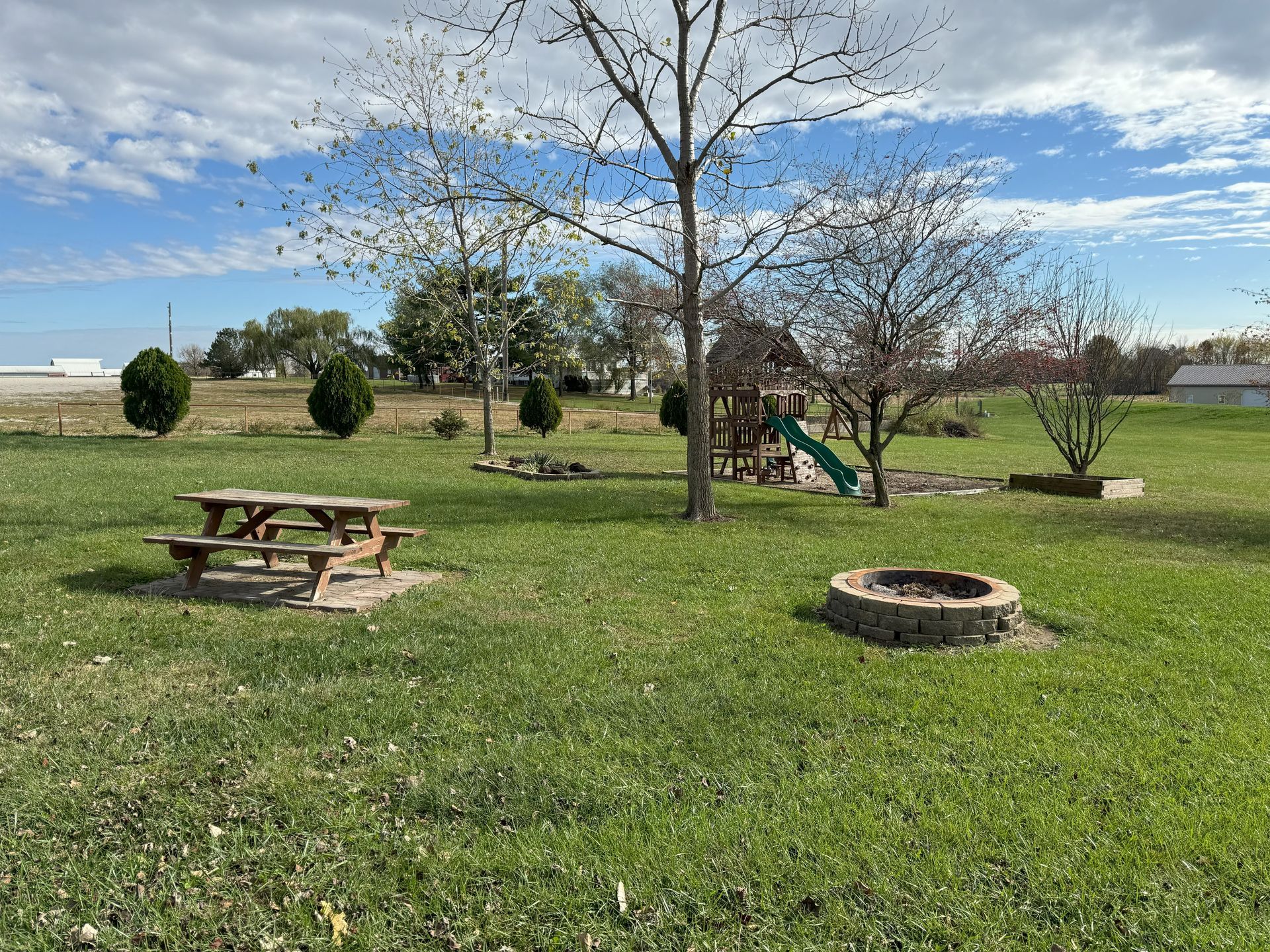 A picnic table and a fire pit in a park.