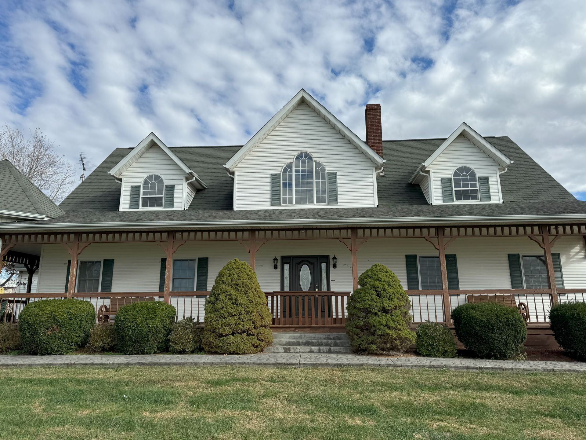A large white house with a porch and a gray roof