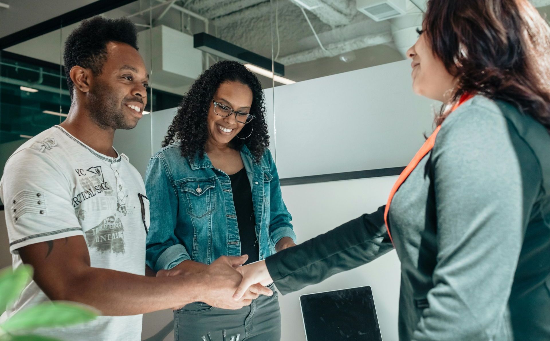 A man and woman are shaking hands with a woman in an office.